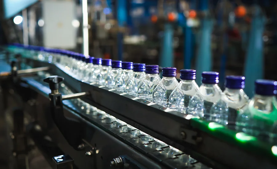 plastic bottles with blue caps on a factory production line.