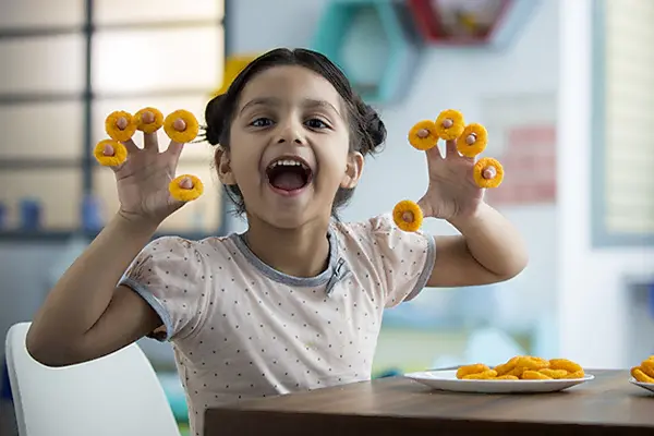 girl smiling and playing with snack