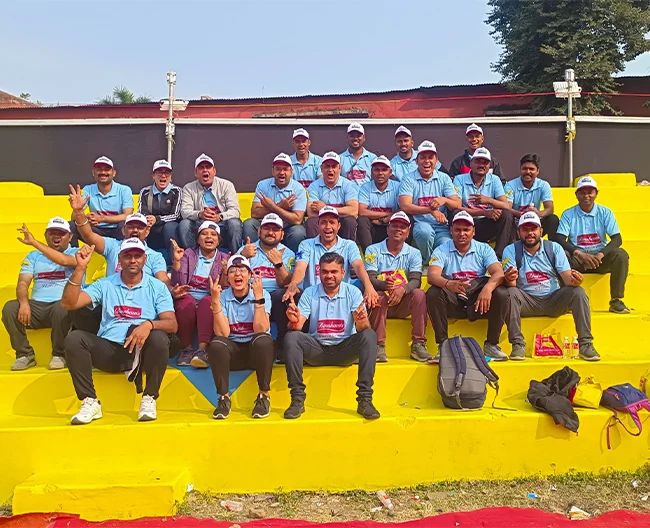 bapuna Group team wearing matching blue t-shirts and caps posing on yellow steps during a walkathon event