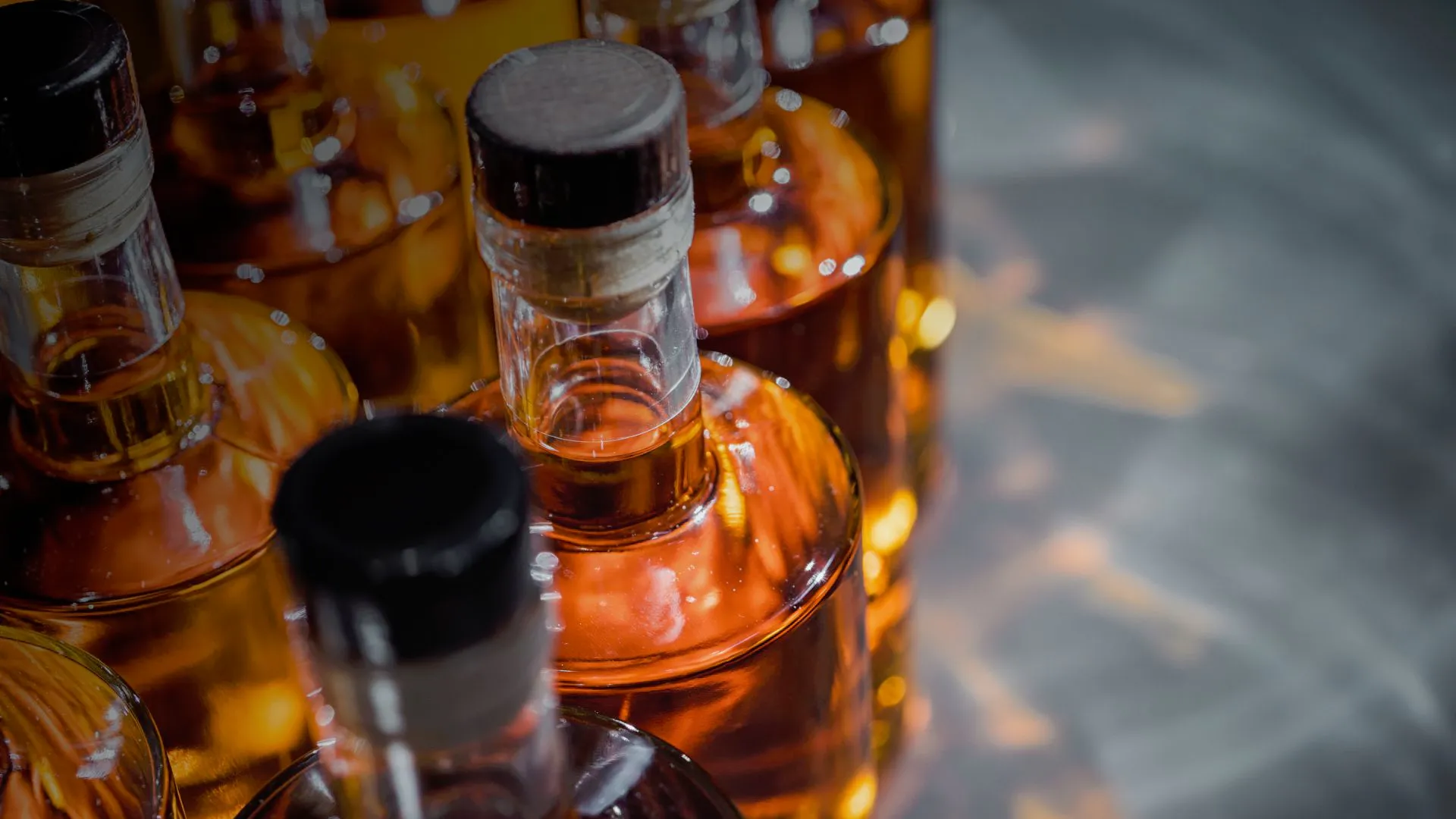 close-up of rum bottles with amber liquid sealed with black caps arranged in a row