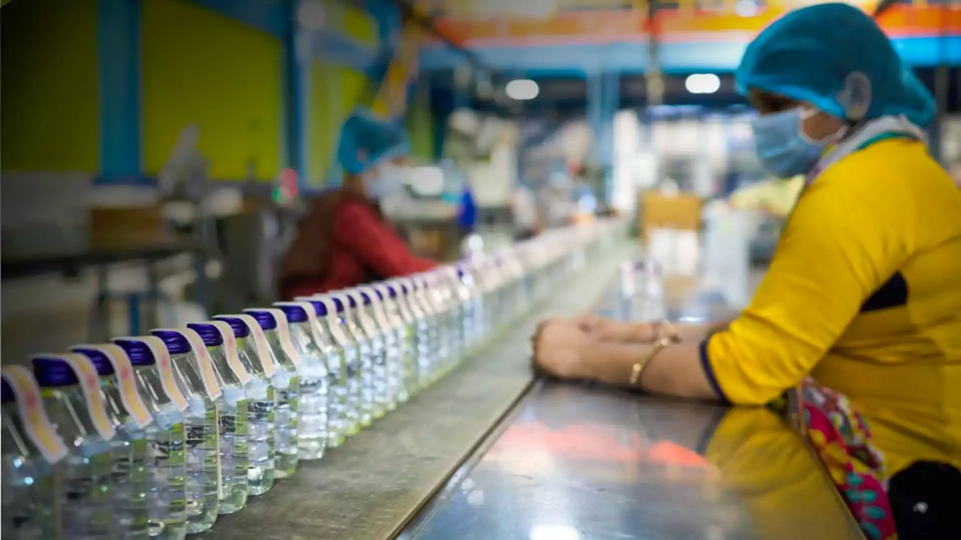 workers in a manufacturing facility inspecting bottled products on a production line