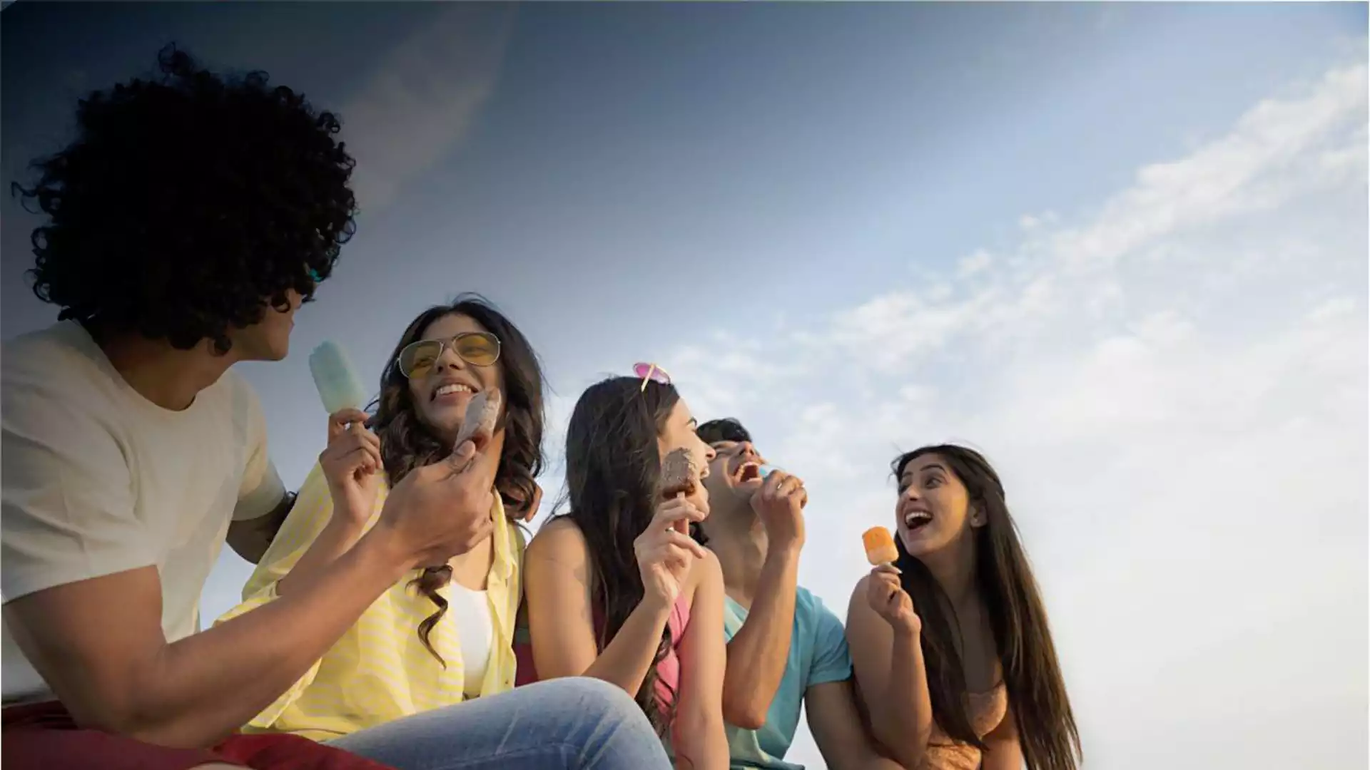 group of young friends enjoying ice cream outdoors on a sunny day
