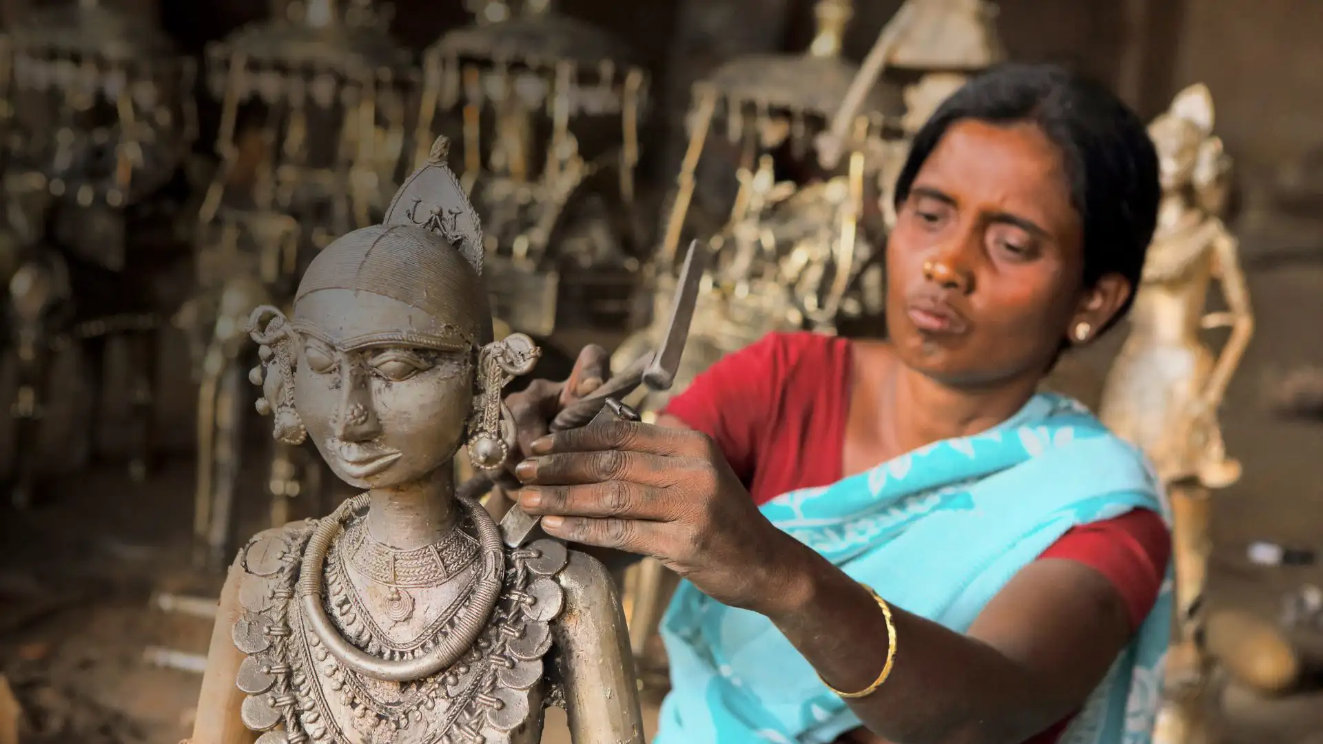 female artisan crafting a detailed metal sculpture showcasing traditional indian handicraft